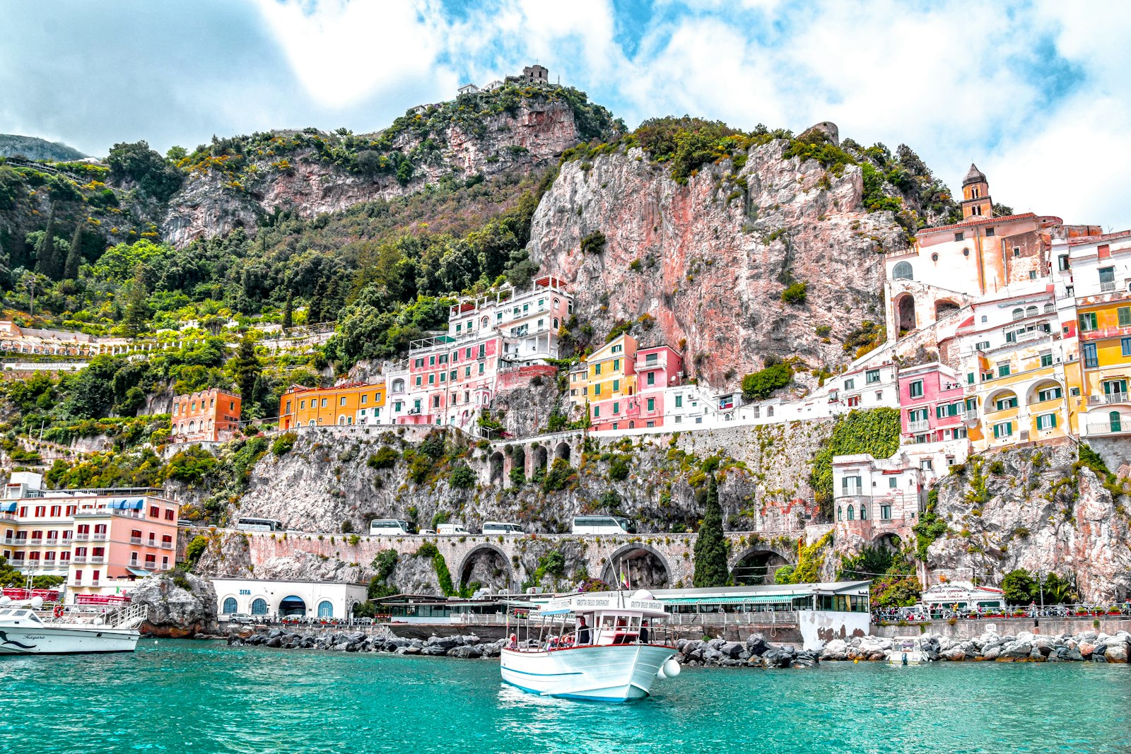 A boat on the water beneath the Amalfi Coast cliffs