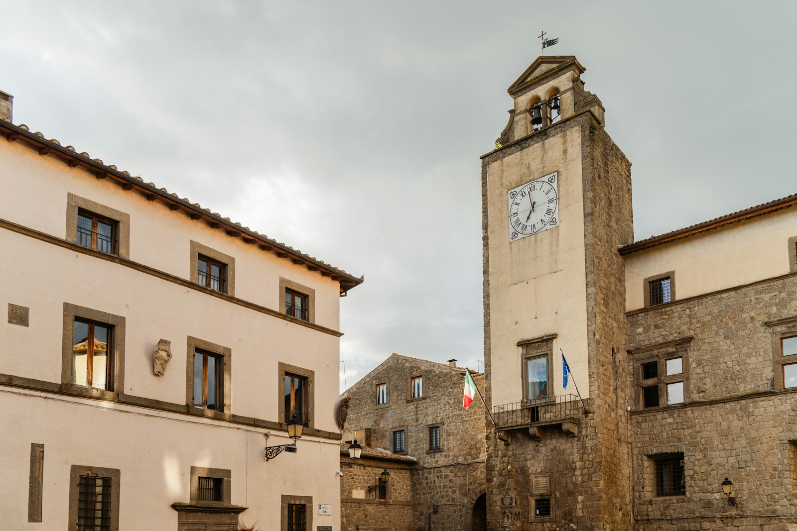A tall bell tower rising above the rooftops of an old town in northern Lazio